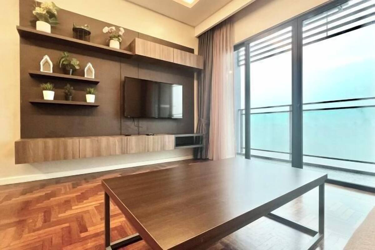 Una sala moderna con una gran mesa de madera, estanterías empotradas con plantas, un televisor de pantalla plana y un amplio ventanal con vistas.