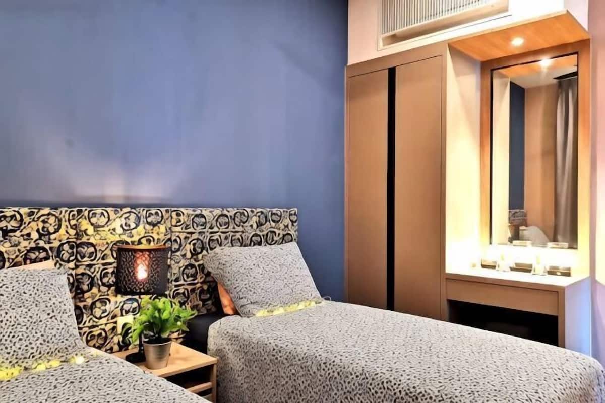 Un dormitorio con un cabecero estampado, mesitas de noche con lámparas y un espejo.