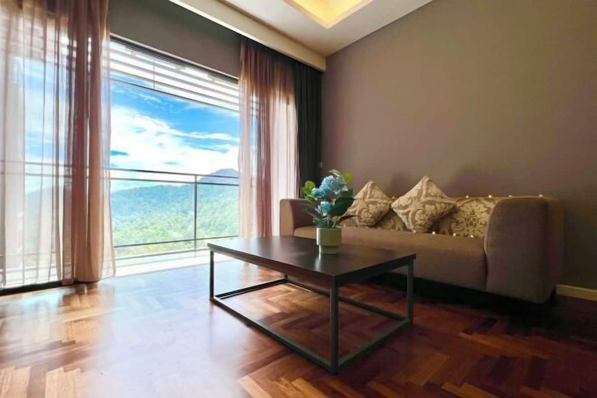 Una sala de estar moderna con suelo de madera, un sofá con cojines estampados, una mesa de centro y vistas a un paisaje montañoso a través de amplios ventanales.