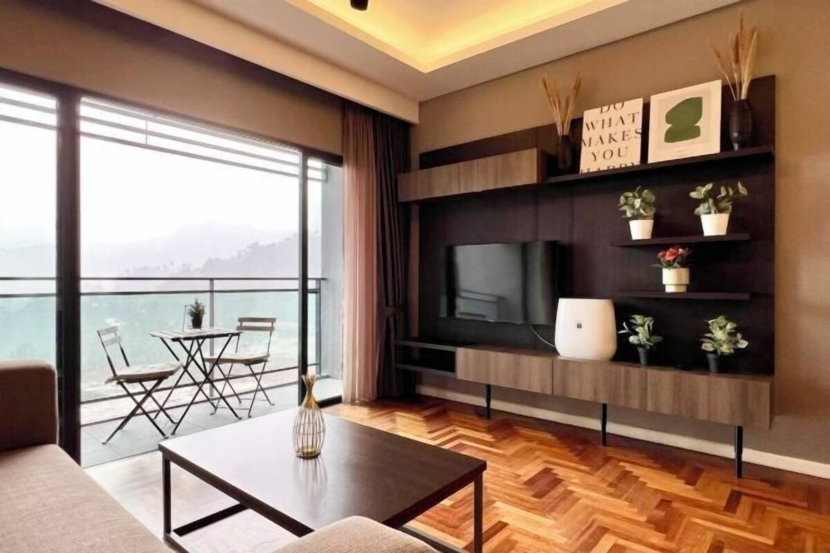 Una sala de estar moderna con un gran ventanal, un televisor de pantalla plana y un suelo de madera en espiga.