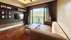 Un salon moderne doté d’un téléviseur à écran plat, d’un ventilateur de plafond, d’un canapé, d’une table basse et d’un balcon offrant une vue sur les montagnes.