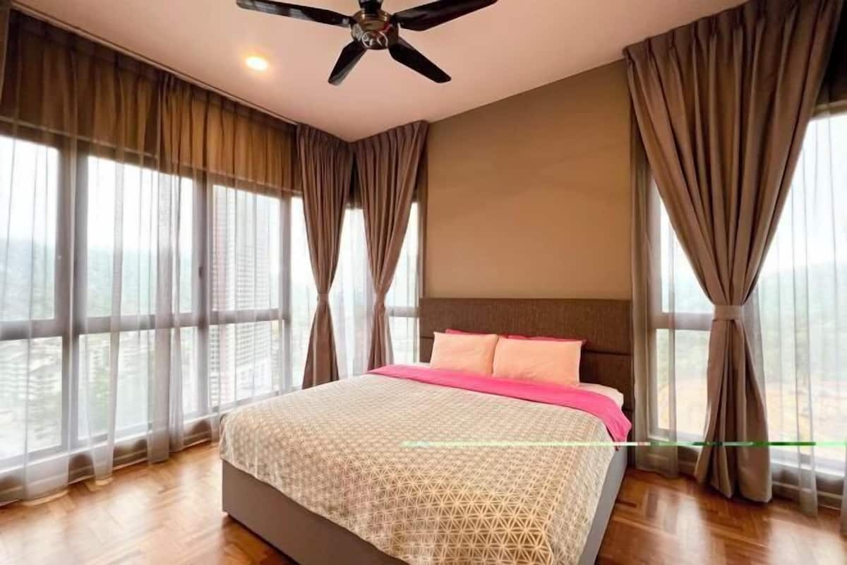 Un dormitorio con cama, cortinas, ventilador de techo y ventanas amplias.