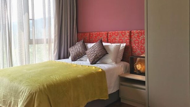 Une chambre d’hôtel avec un lit, une table de chevet, une lampe et une fenêtre avec des rideaux.