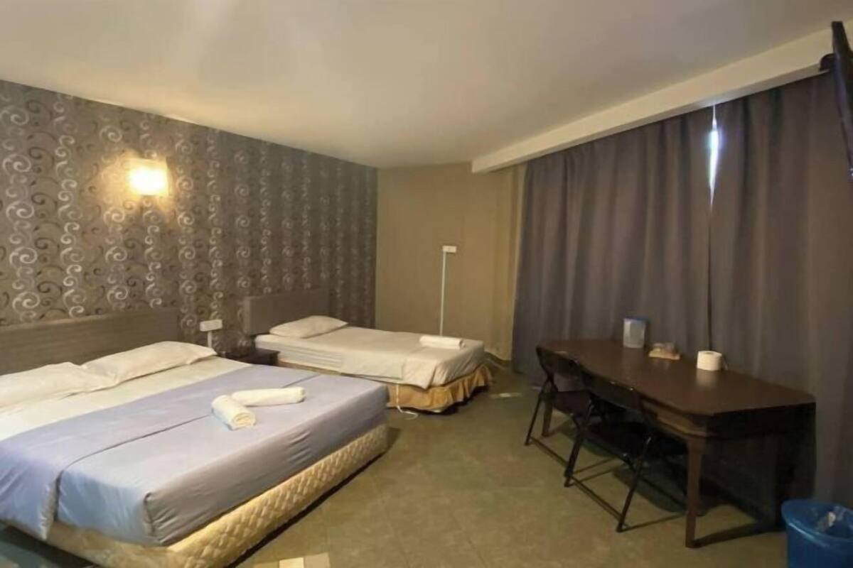 Une chambre d’hôtel avec deux lits, un bureau et une chaise.