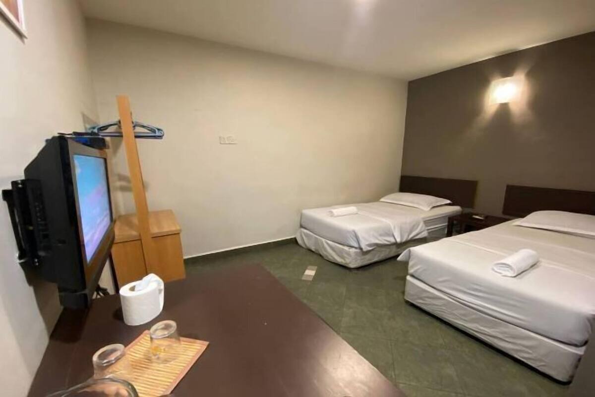 Une chambre d’hôtel équipée d’une télévision, d’un bureau en bois, de deux lits et d’une petite poubelle.