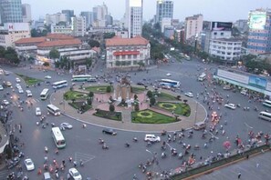A busy urban square with a central monument surrounded by greenery, multiple lanes of traffic, and surrounding buildings. - Lan Anh Hotel (Ho Chi Minh City)