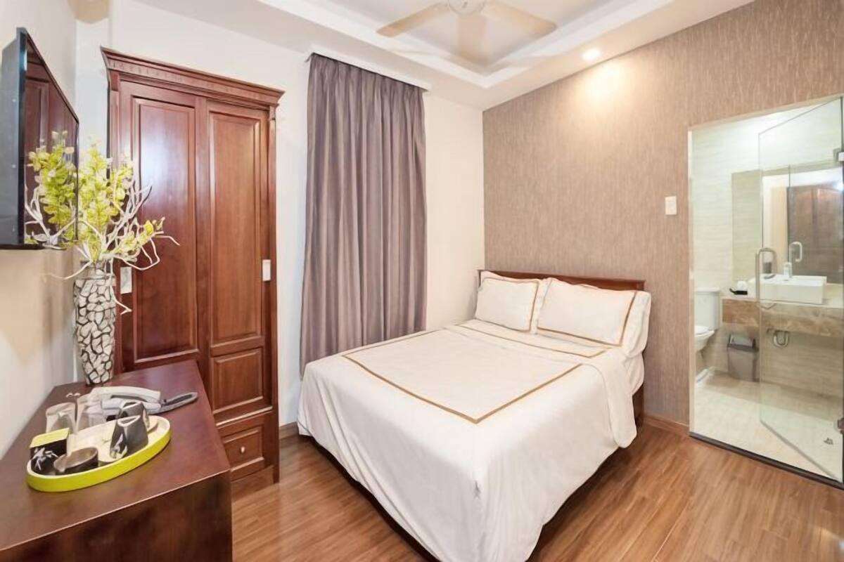 Een hotelkamer met een bed, een bureau met een vaas, een garderobe en een badkamer met een douchecabine.