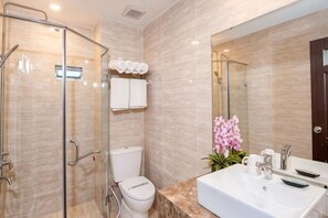 Un bagno moderno con cabina doccia in vetro, un WC, un lavandino con specchio e un'orchidea in vaso.
