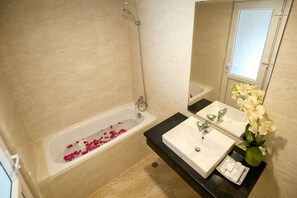 Une salle de bain avec une baignoire, un lavabo et un miroir.