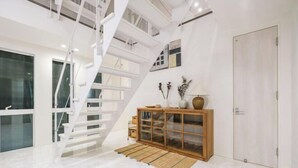 A modern interior with a spiral staircase, a wooden cabinet, and a door. - UN-Villa (Tokyo)