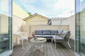 A modern outdoor seating area with a sofa, chairs, and a round table. - UN-Villa (Tokyo)