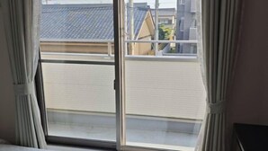 Una habitación con una cama, una ventana con cortinas y vistas a edificios.