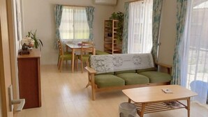 Una sala de estar acogedora con un sofá verde, una mesa de centro de madera y un comedor con mesa y sillas.