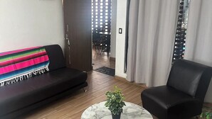 A modern living room with a black sofa, a round marble coffee table with a potted plant, and a black armchair. - The best view of the river & apartament's garden (Orizaba)
