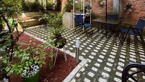 A patio area with two umbrellas, a table, chairs, and potted plants. - The best view of the river & apartament's garden (Orizaba)