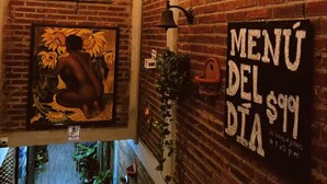 A restaurant interior with exposed brick walls, string lights, a mural, and a menu sign. - The best view of the river & apartament's garden (Orizaba)