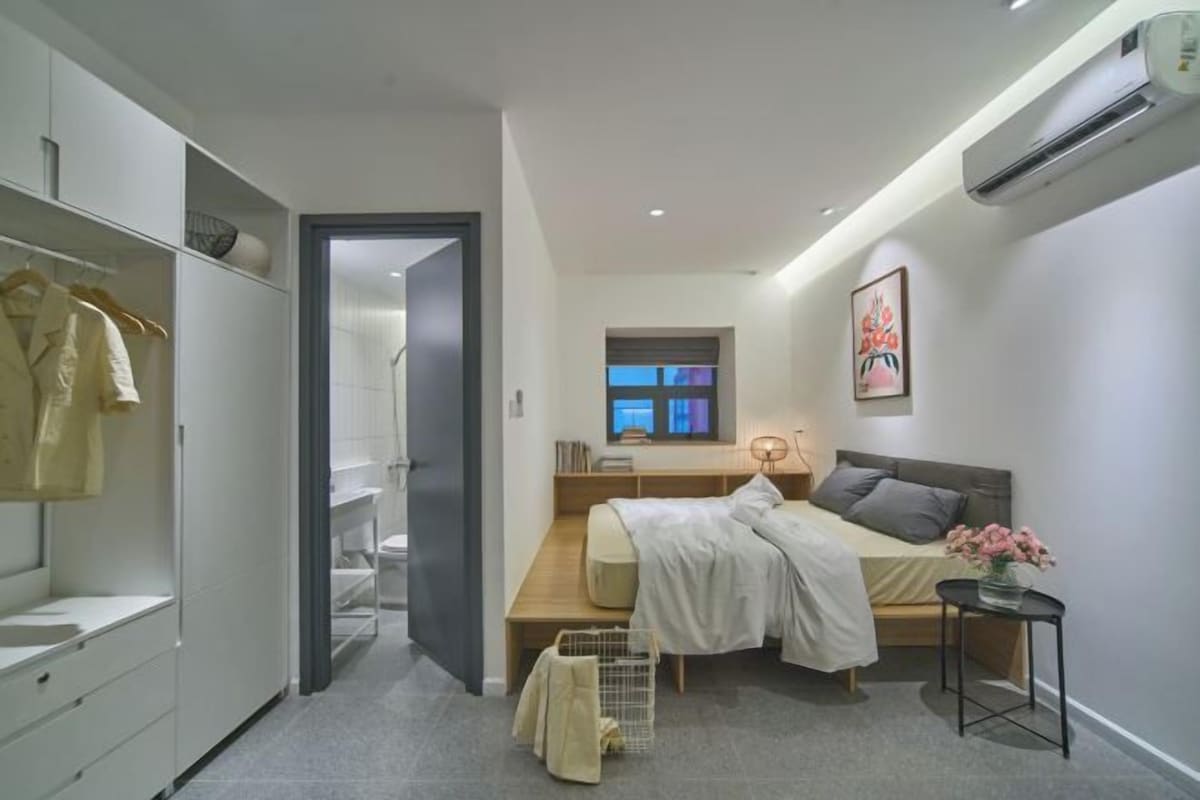 A modern bedroom with a bed, bedside table, and a window.