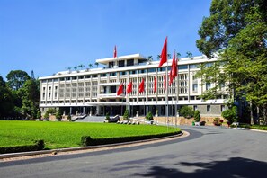 Un grand bâtiment orné de plusieurs drapeaux rouges, avec une pelouse bien entretenue et une allée incurvée.