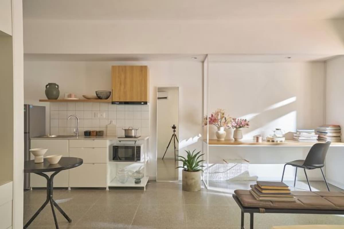 Une cuisine moderne avec des meubles blancs, un plan de travail en bois et un coin repas comprenant une table et des chaises.