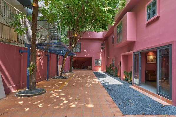 A courtyard with a red building, a staircase, and a seating area. - Express by M Village Ho Bieu Chanh, a brand of Modern Village Lifestyle (Ho Chi Minh City)