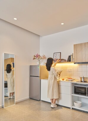 A modern kitchen with a refrigerator, oven, and a person standing by the counter.