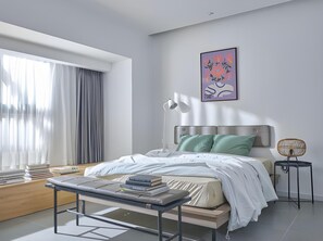 Une chambre à coucher moderne avec un lit, une table de chevet, une lampe et un tableau au mur.
