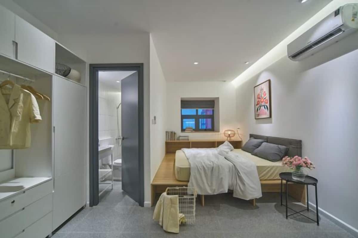 Ein modernes Schlafzimmer mit Bett, Nachttisch und Fenster.