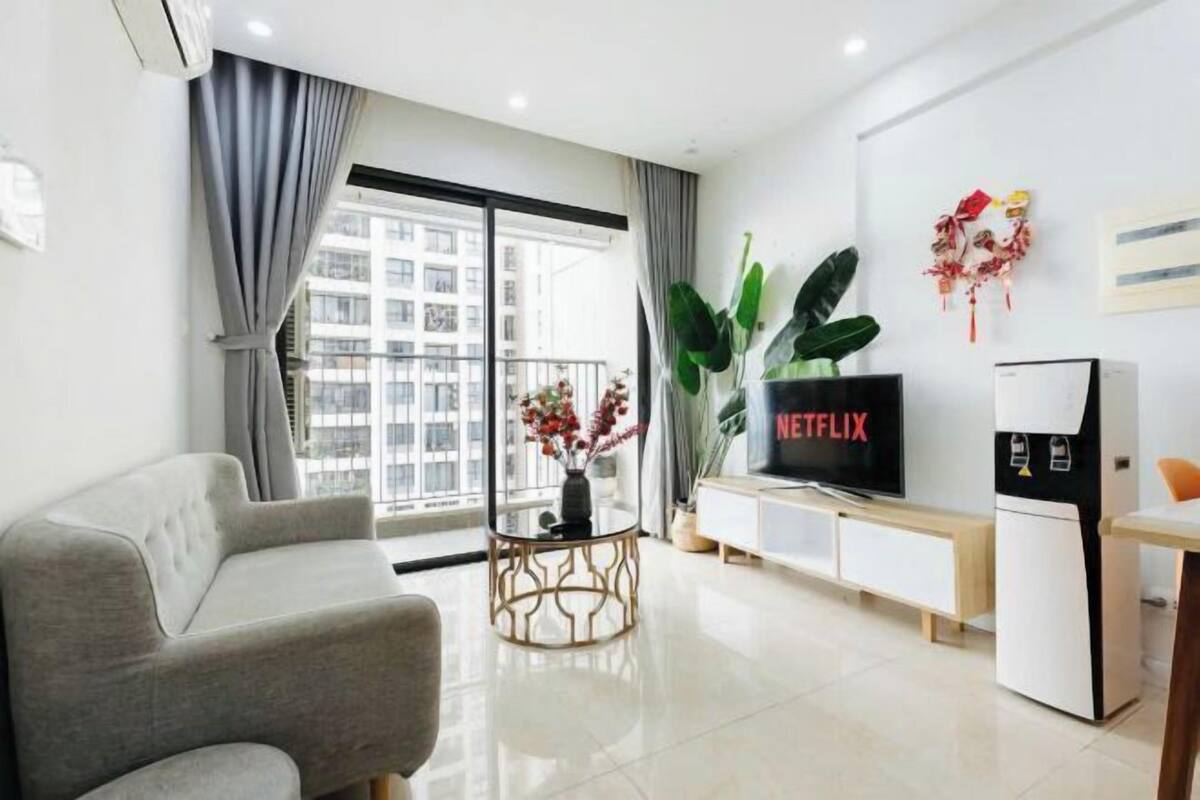 Ein modernes Wohnzimmer mit einer Couch, einem Couchtisch, einem Fernseher und einem kleinen Kühlschrank.