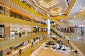 Et stort, flerplans indkøbscenter med rulletrapper, glasgelændere og mange butikker.