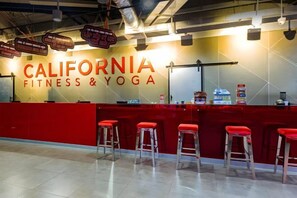 A fitness and yoga studio with a red reception desk and multiple red barstools. - Luxury Serviced Apartment Vinhomes D’Capitale Hanoi – Zen Homes (Hanoi)