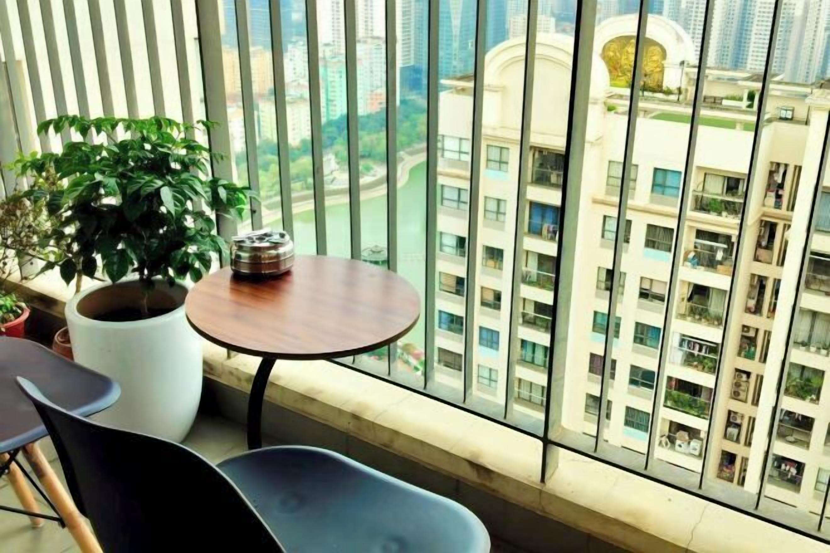 A balcony with a potted plant, a small round table, and two chairs.