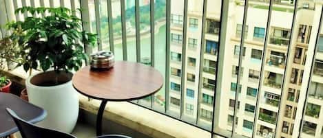 A balcony with a potted plant, a small round table, and two chairs.