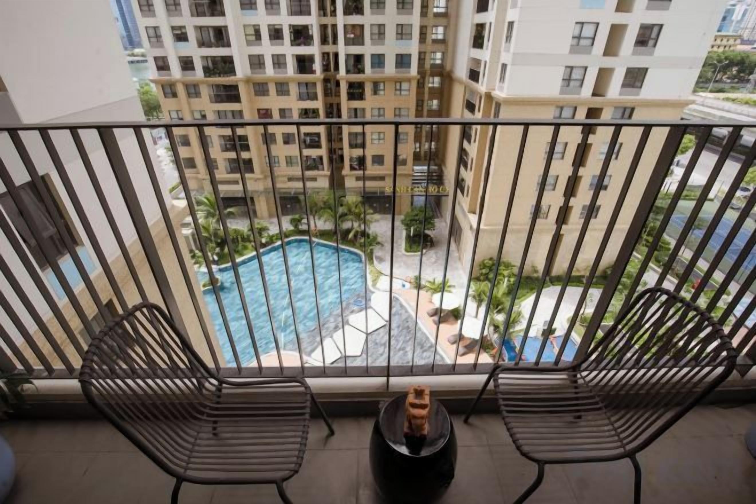 A balcony with a view of a swimming pool and surrounding buildings.