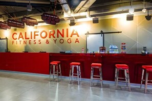 A fitness center with a red reception desk and bar stools. - Luxury Serviced Apartment Vinhomes D’Capitale Hanoi – Zen Homes (Hanoi)