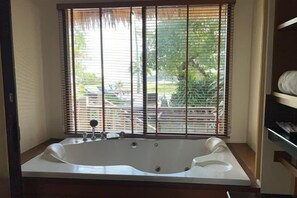 A bathroom with a large bathtub, a window with blinds, and a view of the outside. - Better view koh yao yai (Koh Yao Yai)