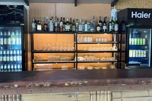 A bar area with shelves of bottles and glasses, a refrigerator, and a Haier branded appliance. - Better view koh yao yai (Koh Yao Yai)