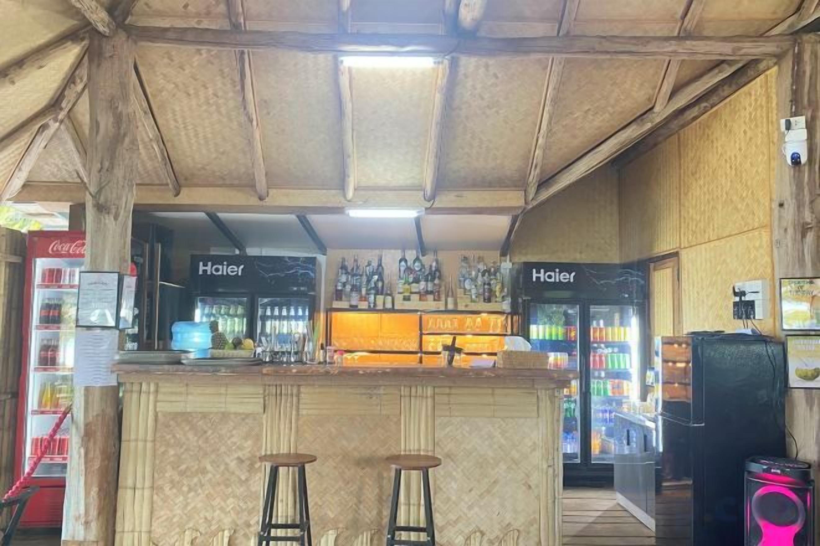 Uma área de bar com banquetas, balcão e geladeira.