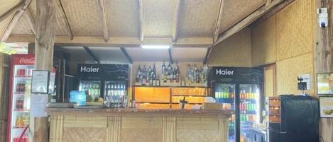 Un espace bar avec des tabourets, un comptoir et un réfrigérateur.