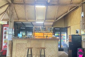 Uma área de bar com banquetas, balcão e geladeira.