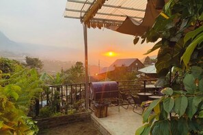 A terrace with a view of the sunset, outdoor seating, and a grill area.