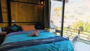 Een houten kamer met een bed, een raam en uitzicht op de omgeving.