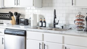 A modern kitchen with white cabinets, a stainless steel dishwasher, a sink, and a coffee machine. - Cozy Stay Near Flint Hills Discovery Center (Manhattan)