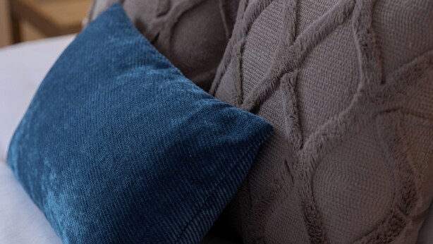 A bed with two pillows, one blue and one brown, in a hotel room. - Cozy Stay Near Flint Hills Discovery Center (Manhattan)