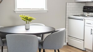 Una cocina moderna con una mesa redonda, sillas grises y una planta en maceta.