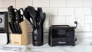 Una cocina con encimera de mármol, un frutero con cuchillos, una especiero y un tostador.