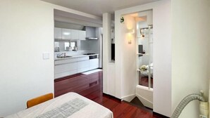 Una cocina moderna con armarios blancos, una mesa de comedor con camino de mesa y un aspirador en la esquina.
