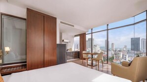 A hotel room with a large bed, a dining area, and a city view. - Diamond Beach Hotel (Da Nang Municipality)
