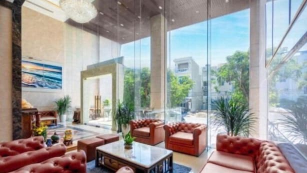 A spacious lobby with leather sofas, a coffee table, and a large window offering a view of the outdoors. - Diamond Beach Hotel (Da Nang Municipality)