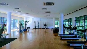 A spacious gym with cardio machines, weightlifting equipment, and large windows offering natural light. - Utopian Residence IMAGO Mall KK (Kota Kinabalu)