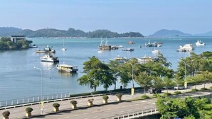 A marina with various boats docked, a road with a guardrail, and a bridge in the background. - Utopian Residence IMAGO Mall KK (Kota Kinabalu)